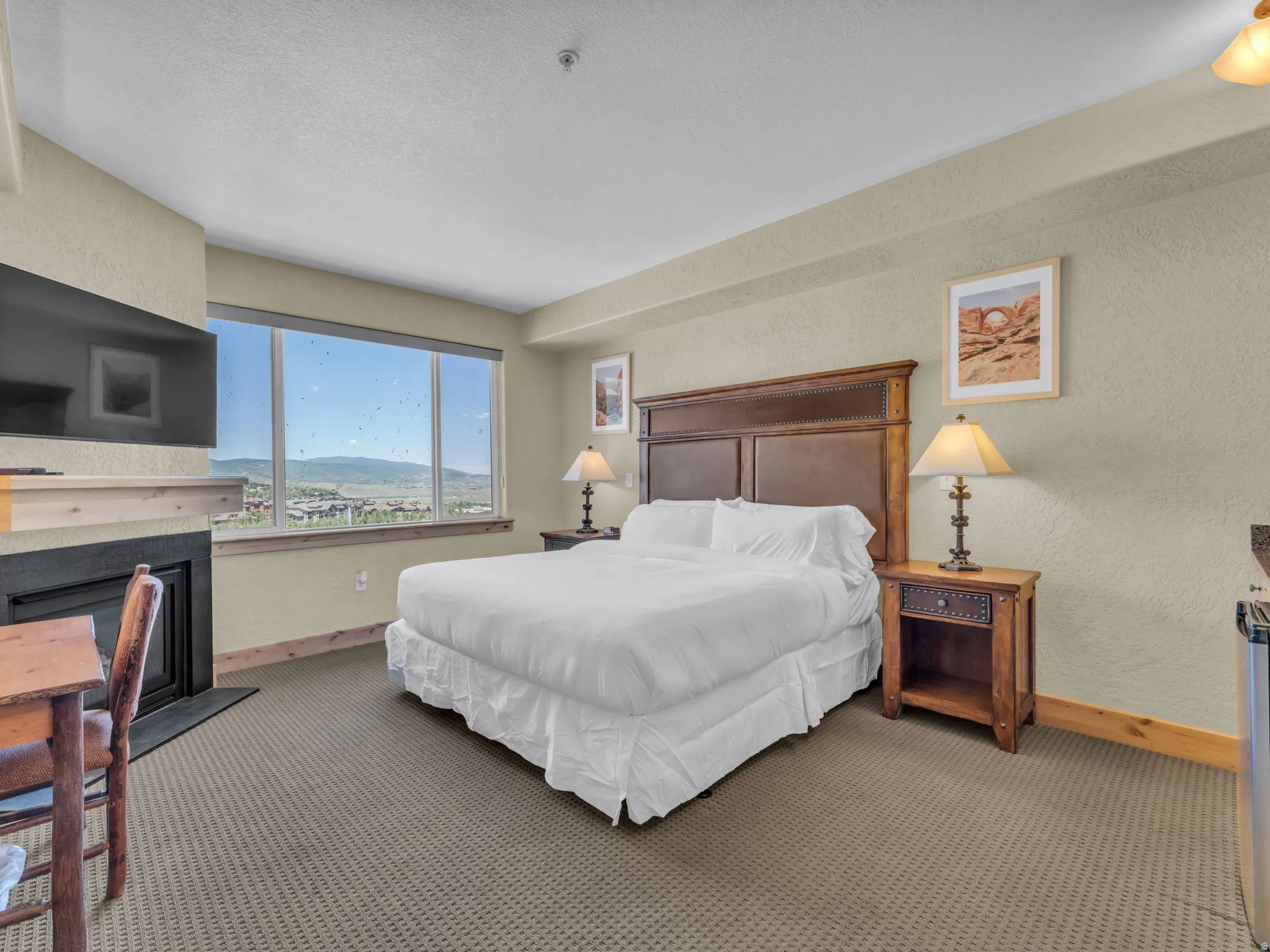 Spacious room with a large window, a built-in fireplace featuring a wood mantel, and plush carpeting