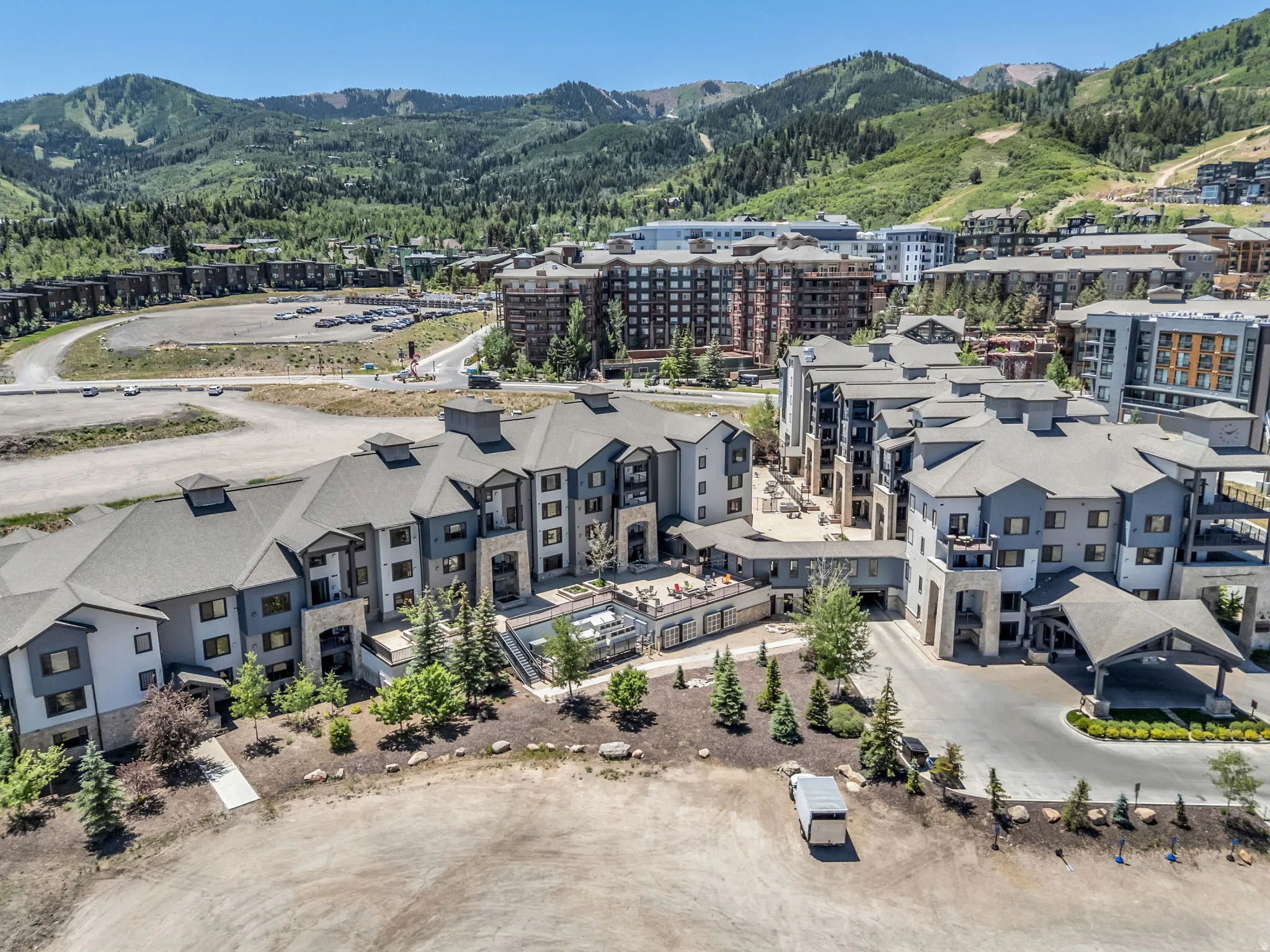 Multi-story residential buildings with pitched roofs, exterior stone accents, a central courtyard pool, and a covered entry