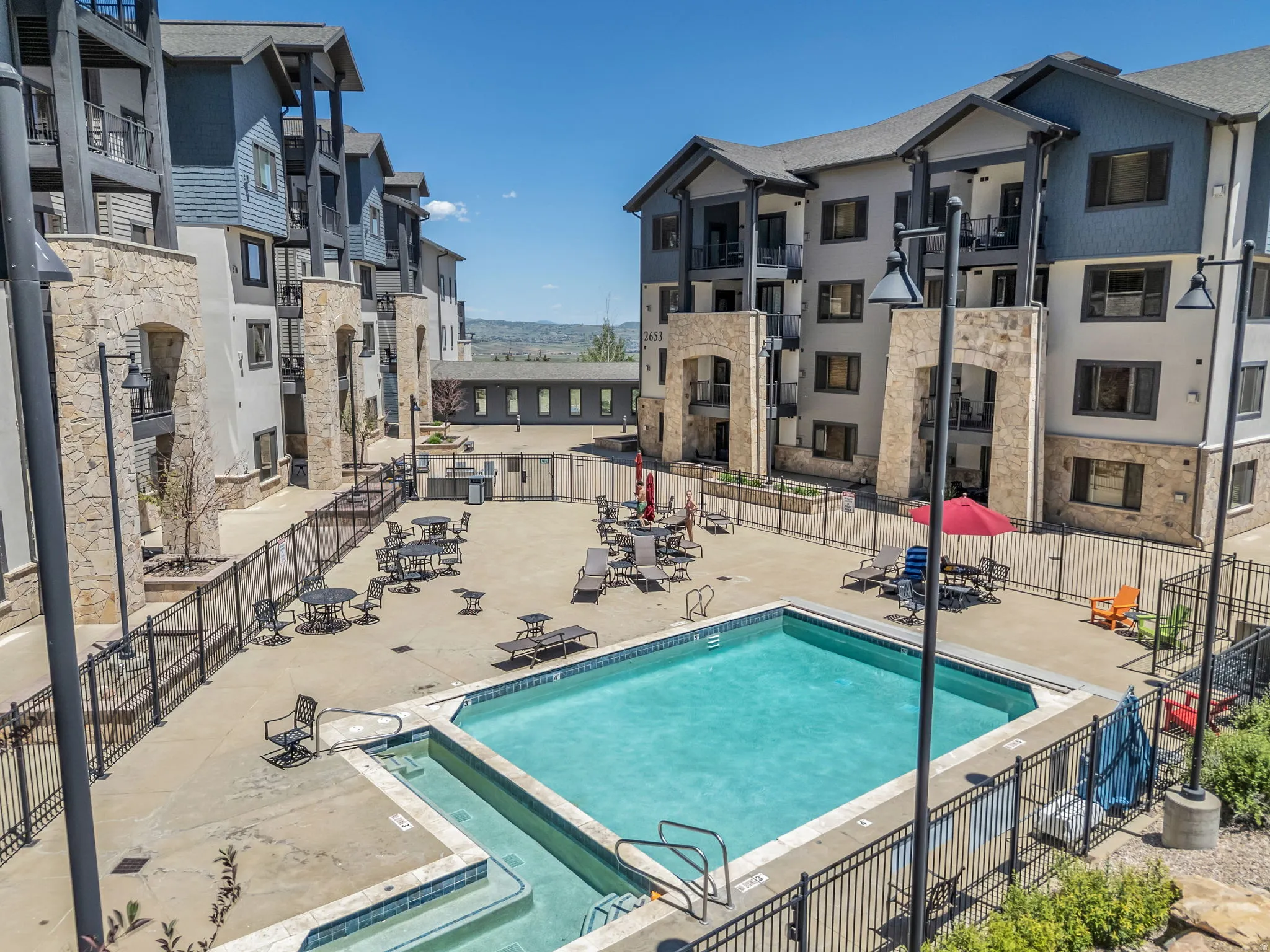 Central courtyard featuring a swimming pool, integrated spa, paved sun deck, and a shared grilling station