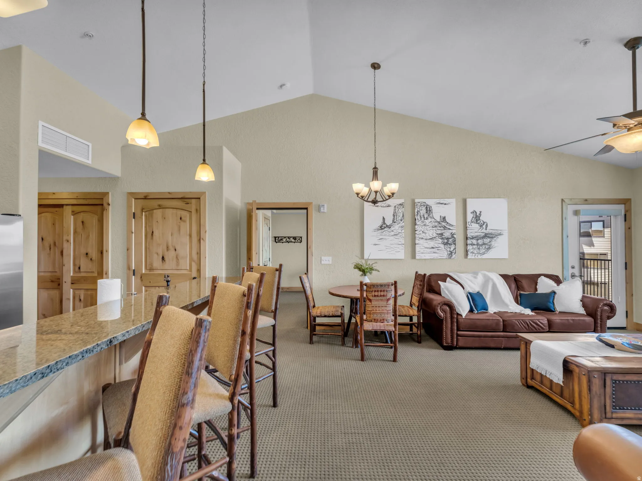 Vaulted ceiling in the living area, breakfast bar with stone countertop, natural wood doors, and recessed lighting