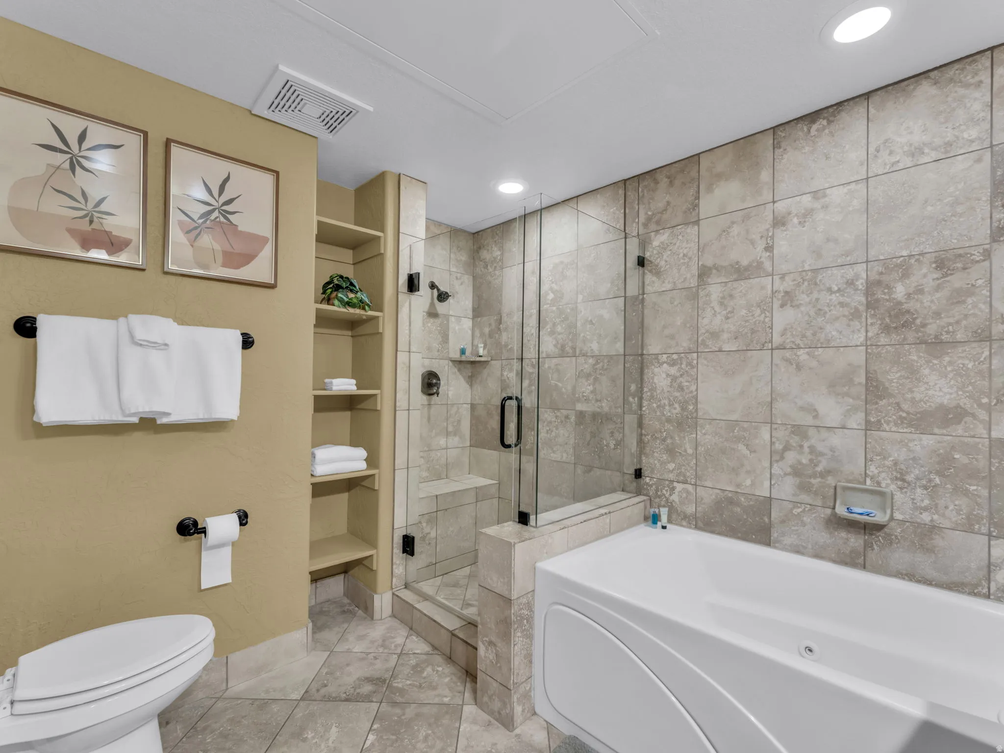 Tiled bathroom featuring a glass-enclosed shower, built-in shelving, a soaking tub, and recessed lighting