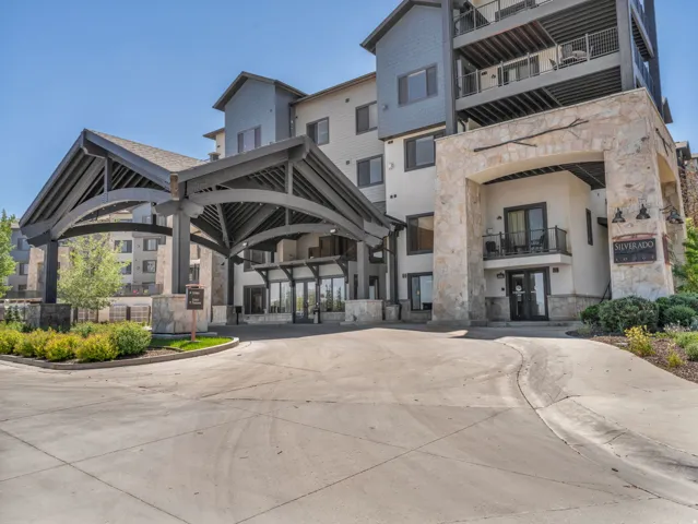 Stone and siding exterior with a covered entry, arched porte-cochère, multiple balconies, and professional landscaping