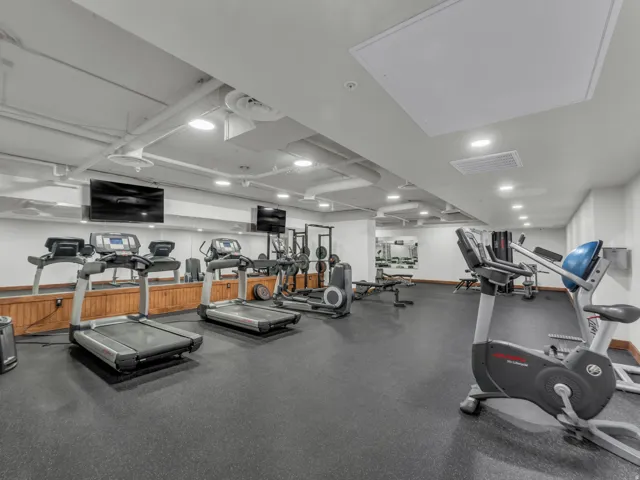 Fitness room featuring rubber flooring, mirrored walls, recessed lighting, and wall-mounted televisions