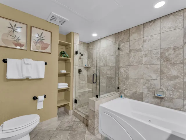 Tiled bathroom featuring a glass-enclosed shower, built-in shelving, a soaking tub, and recessed lighting