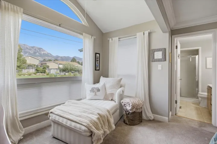 Vaulted ceiling with exposed beam, large picture window with arched transom, neutral wall finishes, and carpeted flooring