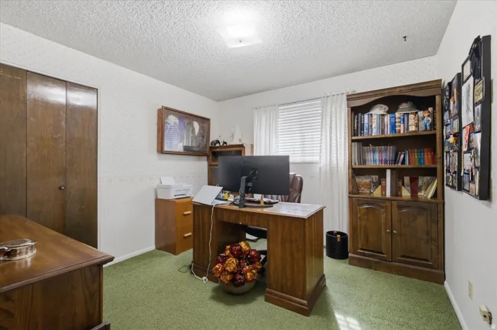 Built-in wood-finish shelving, wood-finish desk, wood-finish closet doors, window with blinds.