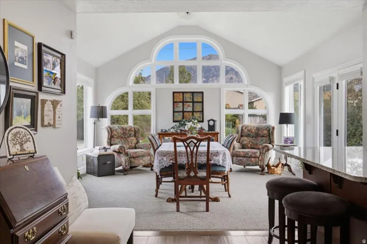 Vaulted ceiling with a large arched window, multiple casement windows, French doors, wood-finish flooring, and a built-in breakfast bar