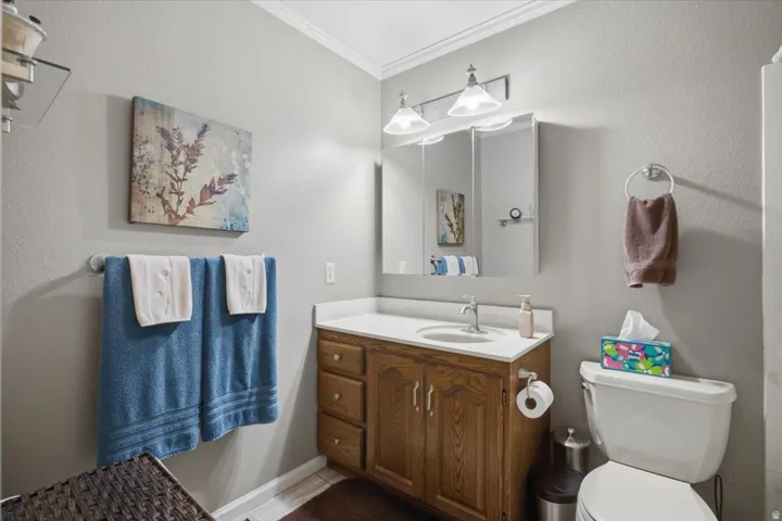 Vanity with a white countertop and wood-finish cabinetry, illuminated by a multi-bulb light fixture