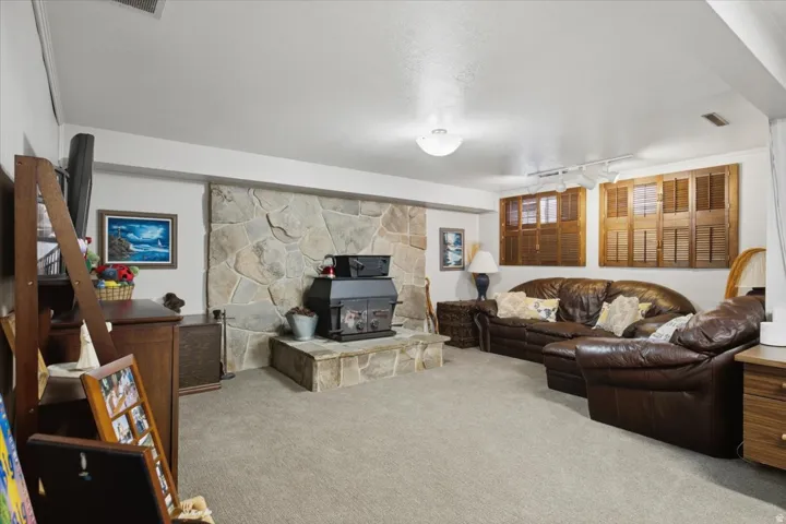 Stone-clad fireplace with a hearth, wood-burning stove, and overhead lighting