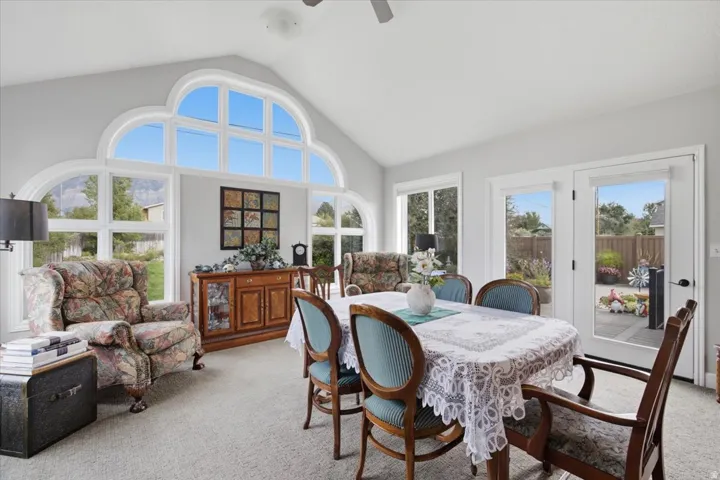 Vaulted ceiling with an arched window wall, French doors, and carpet flooring
