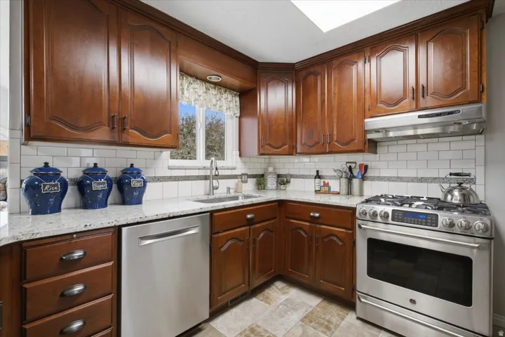 Kitchen featuring wood cabinetry, stainless steel appliances, a subway tile backsplash, and light-toned countertops