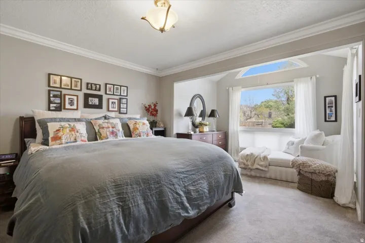 Crown molding, recessed alcove with arched window, and carpeted flooring