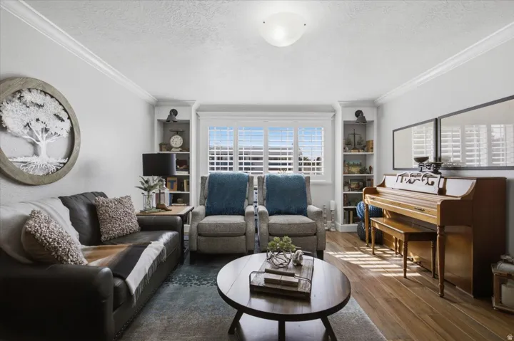 Wood-finish flooring, crown molding, built-in shelving, and window shutters