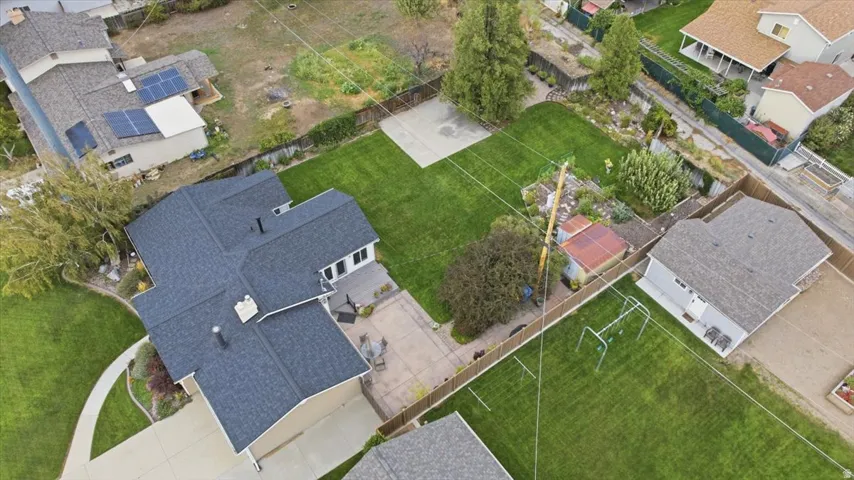 Expansive property featuring a dark shingle roof, paved patio area, and a large lawn with mature trees