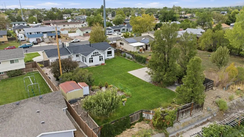 Expansive lot with a large green lawn, mature trees, and a detached storage shed