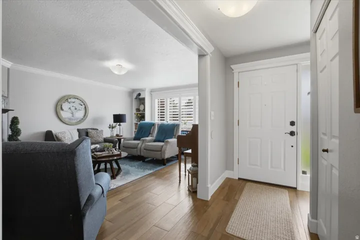 Wood-finish flooring throughout, white crown molding, recessed lighting fixtures, built-in shelving, and white plantation shutters