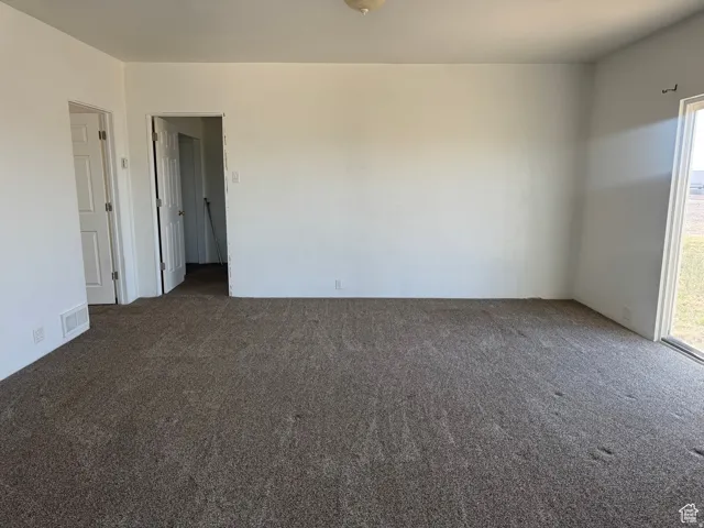 Neutral-toned wall-to-wall carpeting, white walls, and a sliding glass door