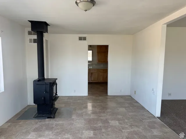 Black wood-burning stove with a protective hearth pad, recessed ceiling light fixture, and tile flooring