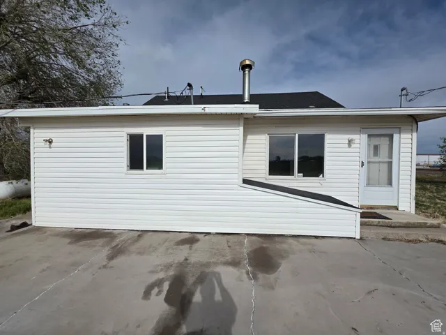 White vinyl siding exterior with multiple windows and a side entry door, featuring a concrete pad