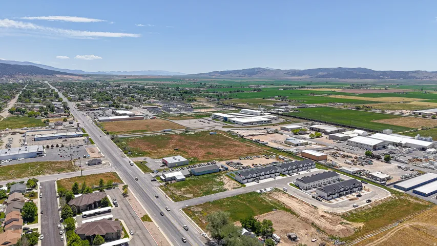 Expansive aerial perspective showcasing residential properties, commercial structures, and undeveloped land