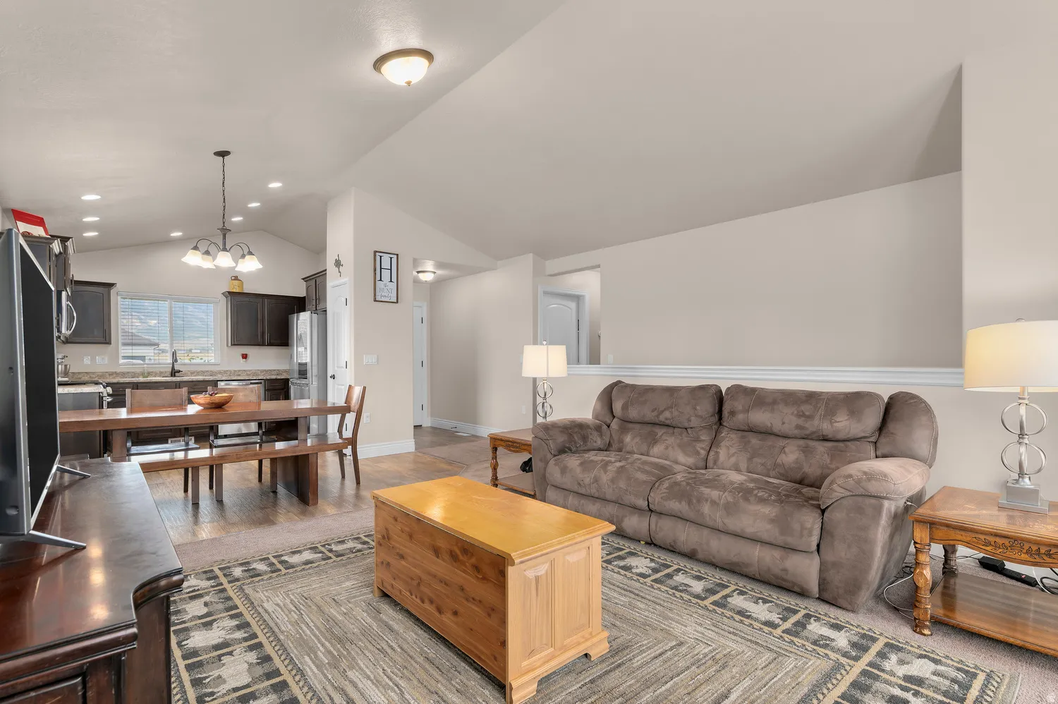Open-concept living area featuring a gray upholstered sofa, wood-finish coffee table, and geometric area rug anchoring the space