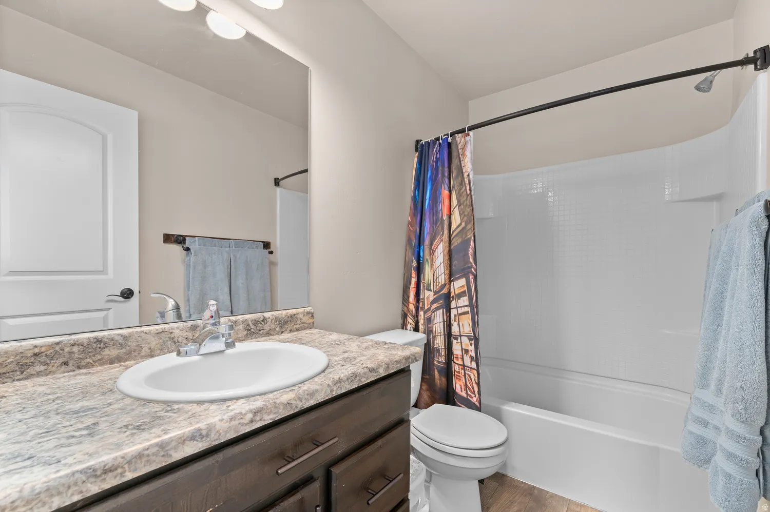 Bathroom featuring a vanity with an oval sink, dark wood-finish cabinetry, and a shower/tub combination with a white surround