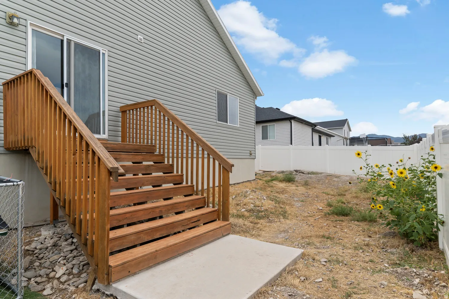 Wood-tone exterior staircase with railing, leading to a sliding glass door