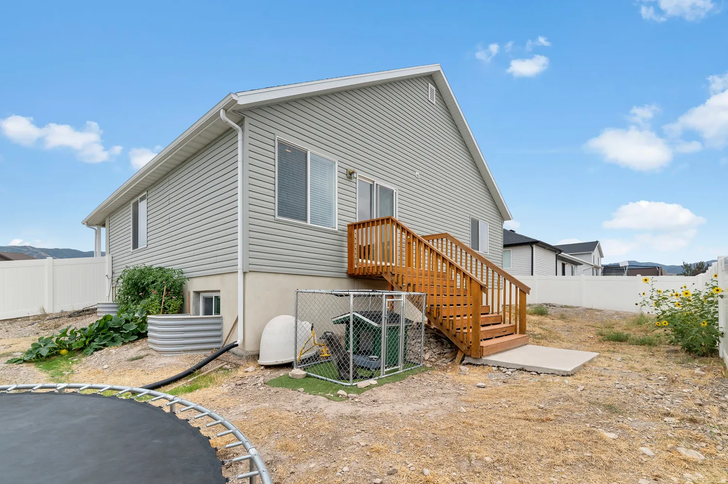 Elevated wood-finish deck with sturdy railings providing outdoor access from the main level, complemented by a manicured front yard and concrete driveway