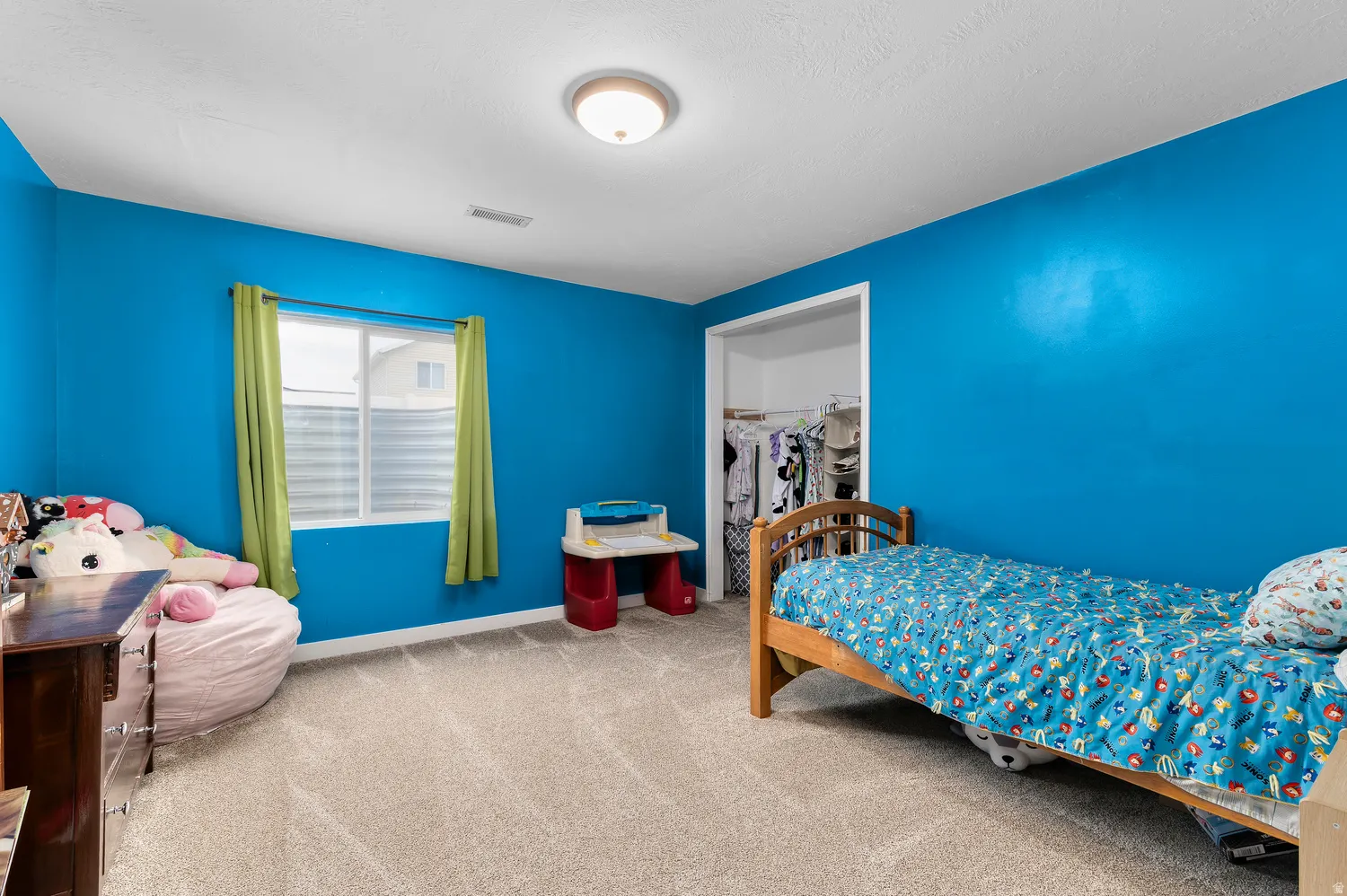 Carpeted room with a single window, overhead lighting, and an open closet