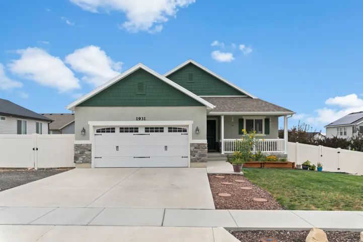 Contemporary home with a two-car garage, stone façade accents, and a covered front porch