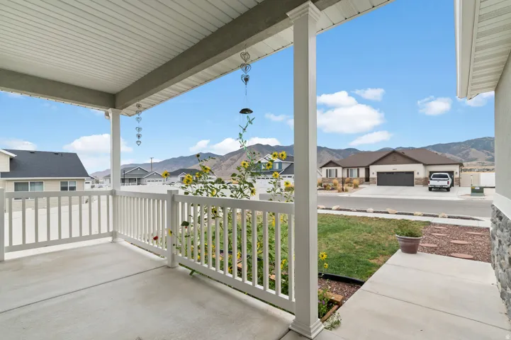Covered front porch with white railing, concrete flooring, and stone facade accents