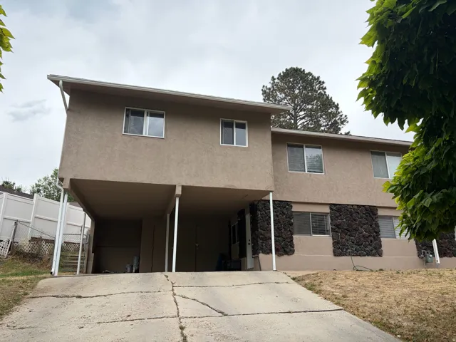 Stucco exterior with stone accents, covered parking, and an extended driveway