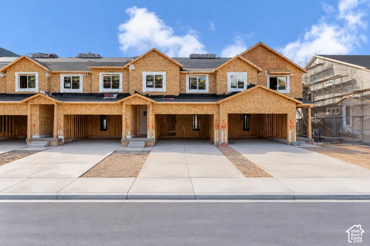 Multi-unit residential structure featuring wood-frame construction, multi-gabled rooflines, white-framed windows, and dedicated concrete driveways