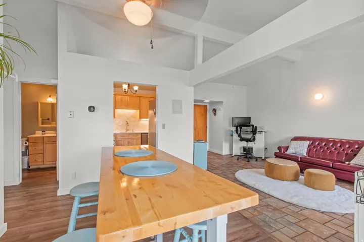 Vaulted ceilings with exposed beams, wood-finish flooring, and a kitchen featuring wood cabinetry and an undermount sink