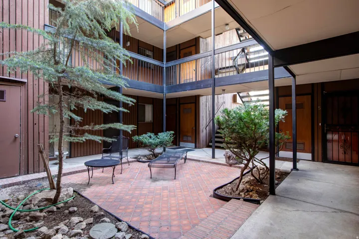 Courtyard area featuring brick paving, mature trees, and multi-level walkways with metal railings