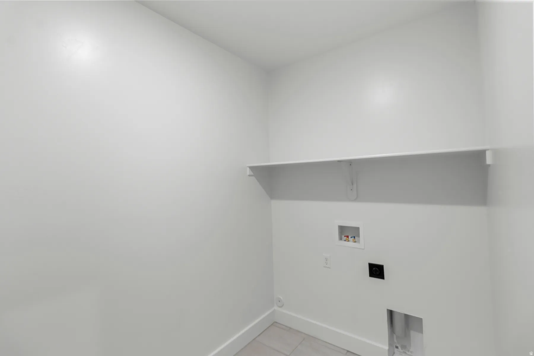 Utility area featuring a built-in shelf, appliance hookups, and tiled flooring