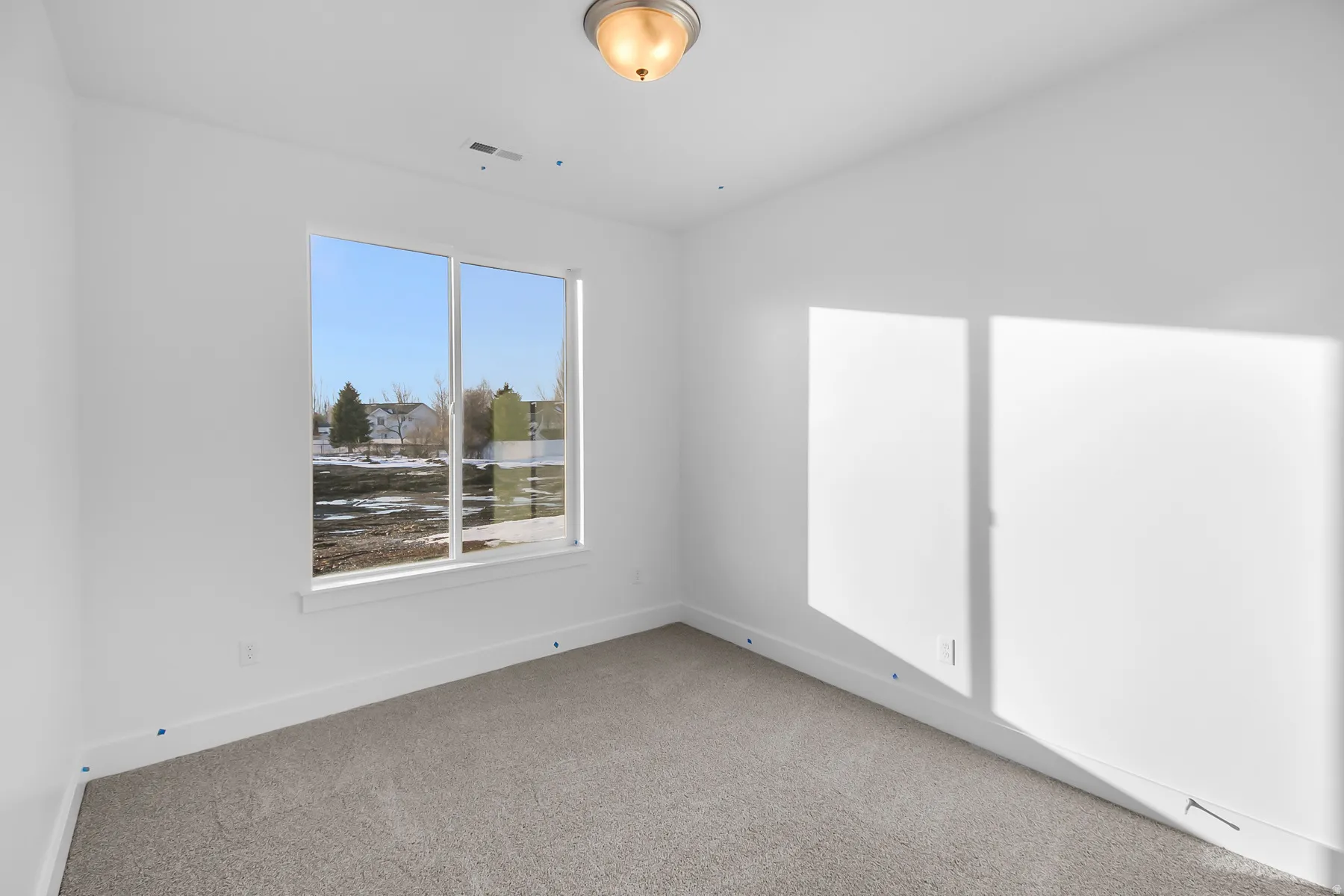 Single-pane window with white trim, light gray carpet, and a flush-mount ceiling light fixture
