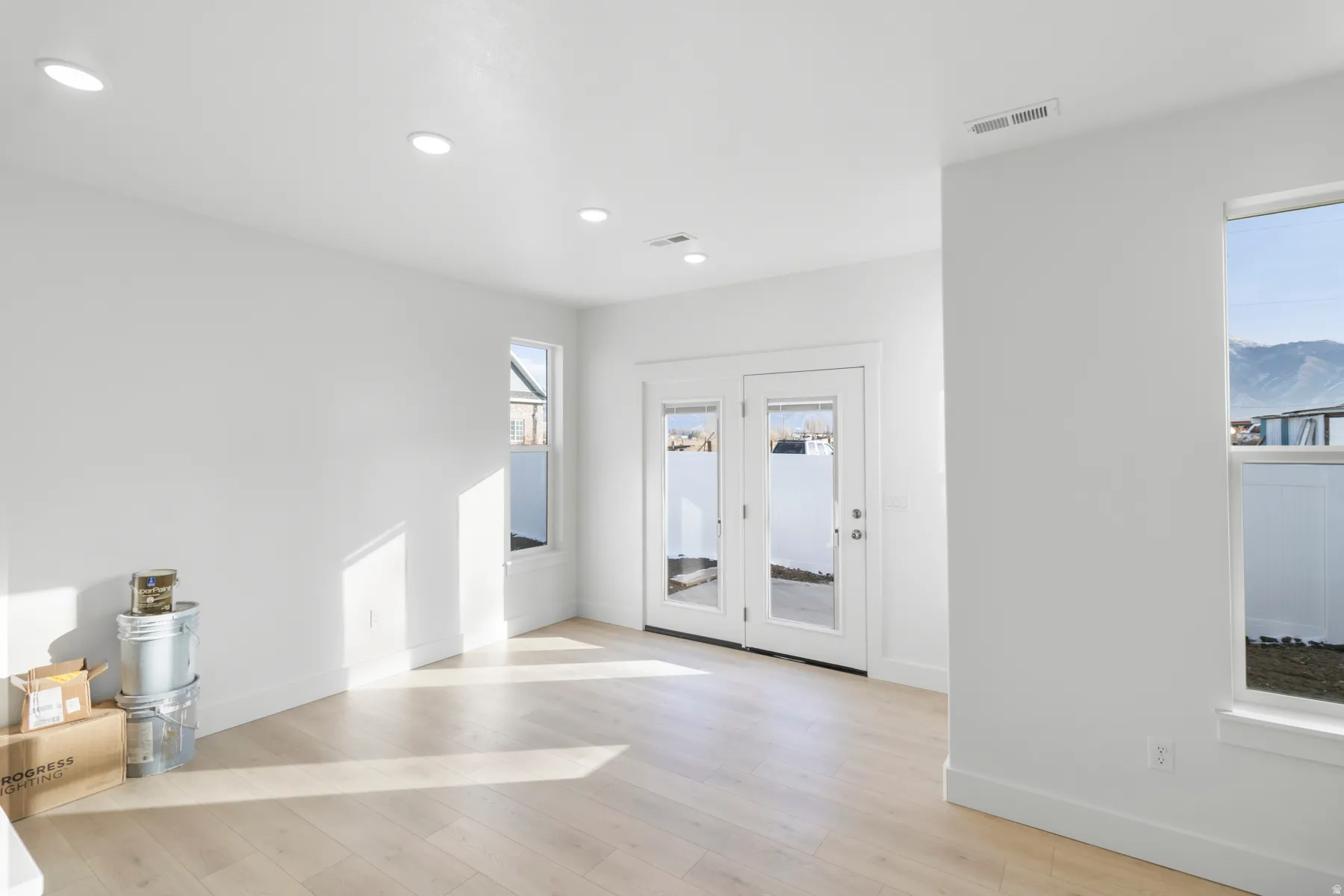 Recessed ceiling lighting, light wood-finish flooring, white walls, and dual glass-panel doors