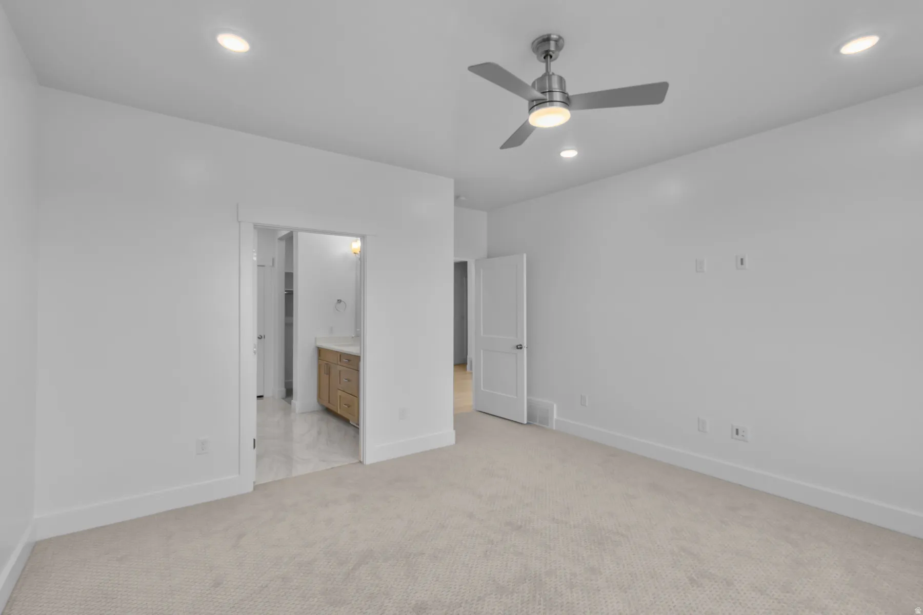 Neutral-toned carpeting throughout, complemented by recessed ceiling lights and a contemporary ceiling fan