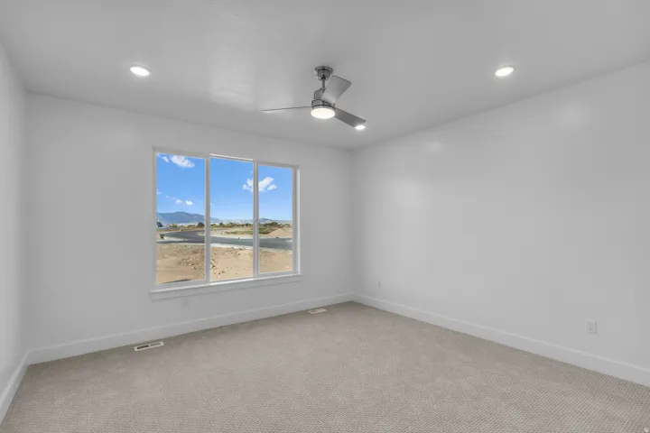 Large window with white trim, recessed ceiling lighting, a ceiling fan with integrated lighting, and neutral carpeting