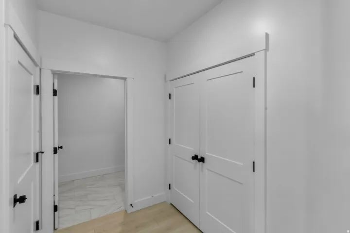 White interior doors with matte black hardware, light-toned wood-finish flooring, and white wall finishes