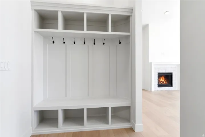 Built-in mudroom storage with hooks and cubbies, light wood-finish flooring, and a fireplace with a stone surround