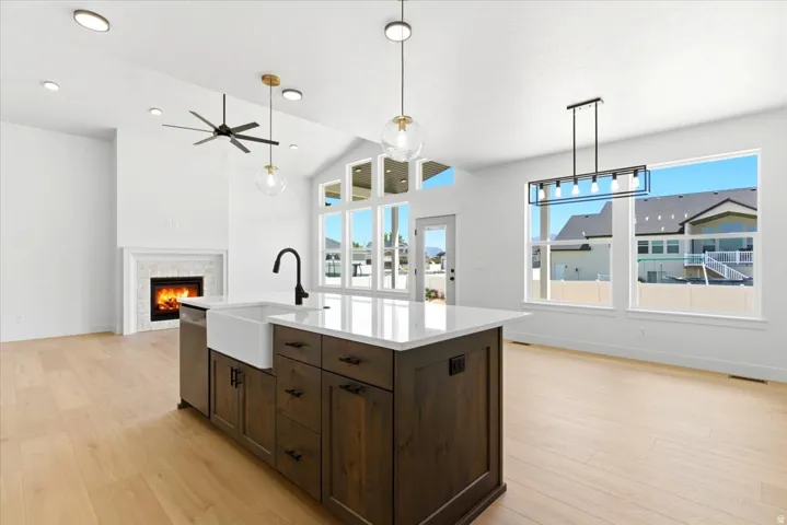 Kitchen island featuring a farmhouse sink, dark wood cabinetry, and a light-toned countertop