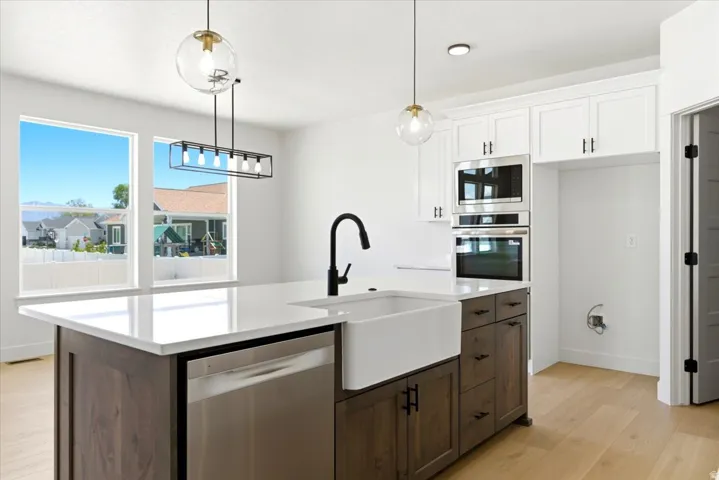Kitchen featuring a large island with a farmhouse sink, stainless steel dishwasher, and built-in microwave and oven