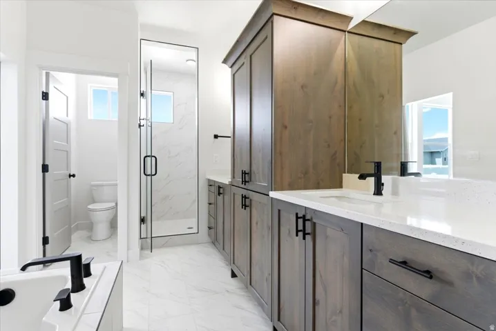 Dual vanity with integrated sinks, wood-finish cabinetry, frameless glass shower enclosure, and a built-in soaking tub