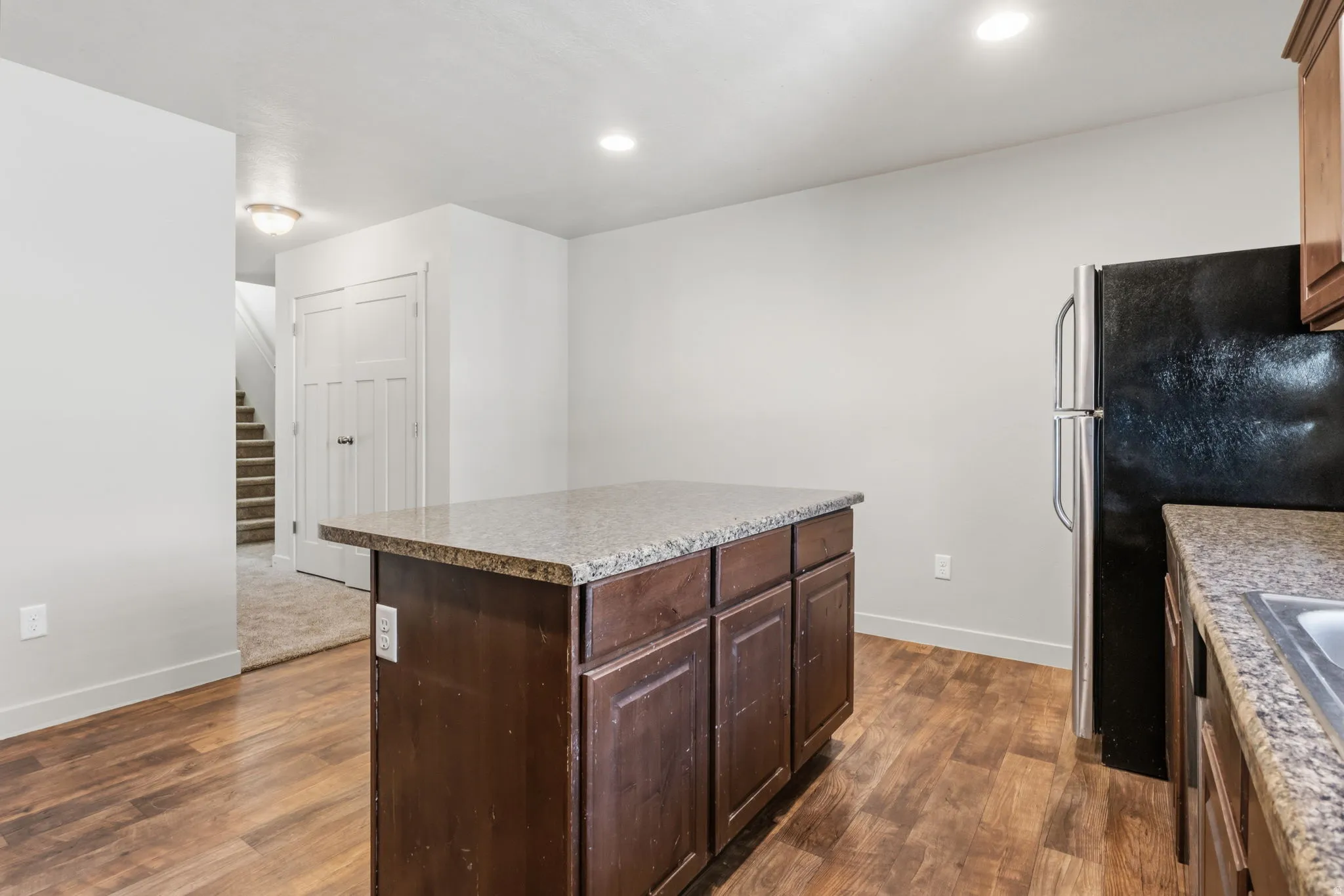 Kitchen featuring a central island with wood-finish cabinetry, stone countertops, and recessed lighting