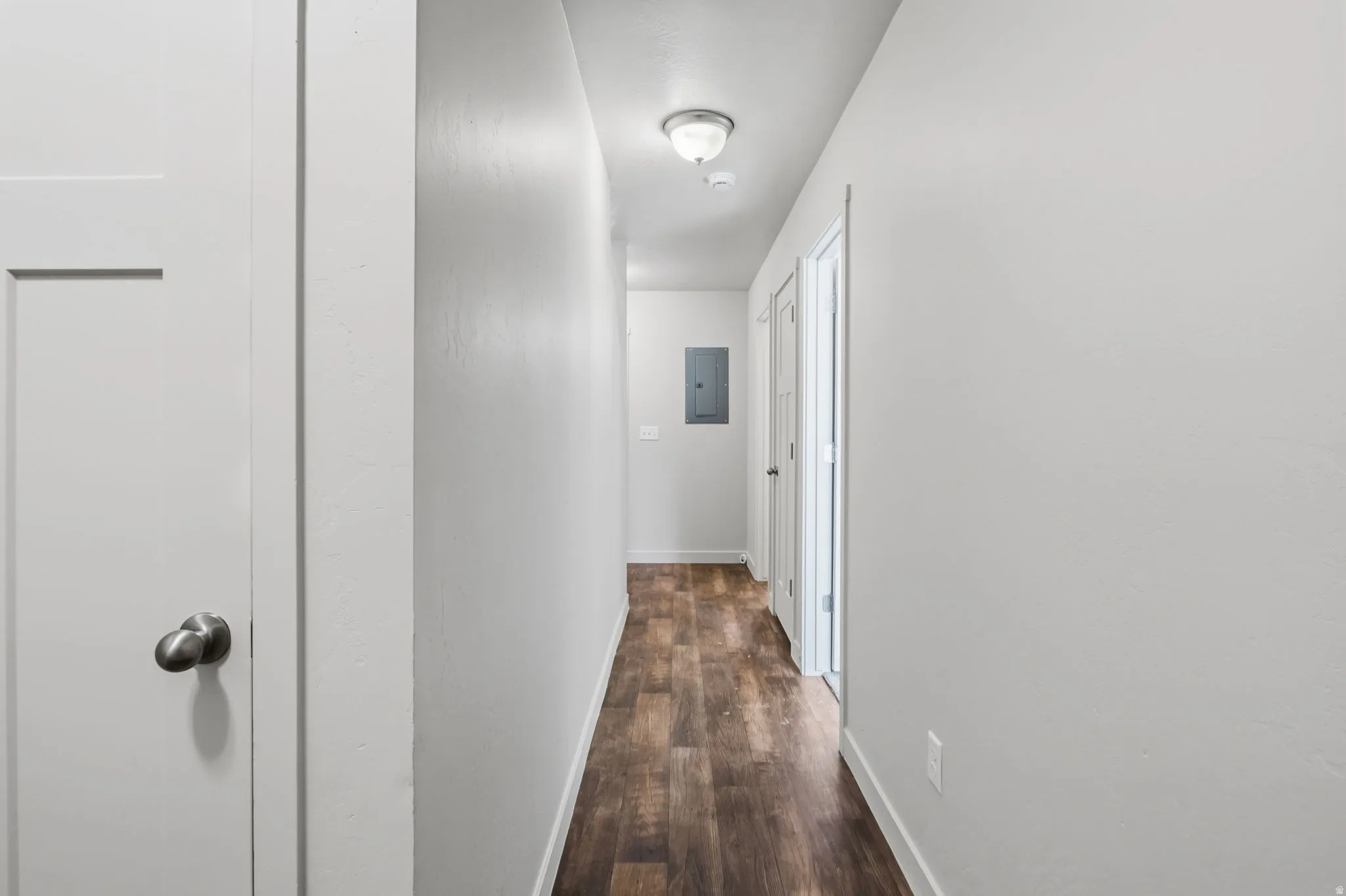 Hallway featuring wood-finish flooring, light neutral paint, and white trim