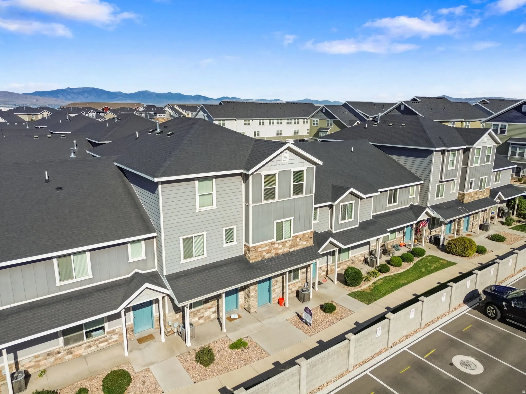 Row of townhomes featuring multi-tone siding, stone accents, covered entryways, and a structured parking area