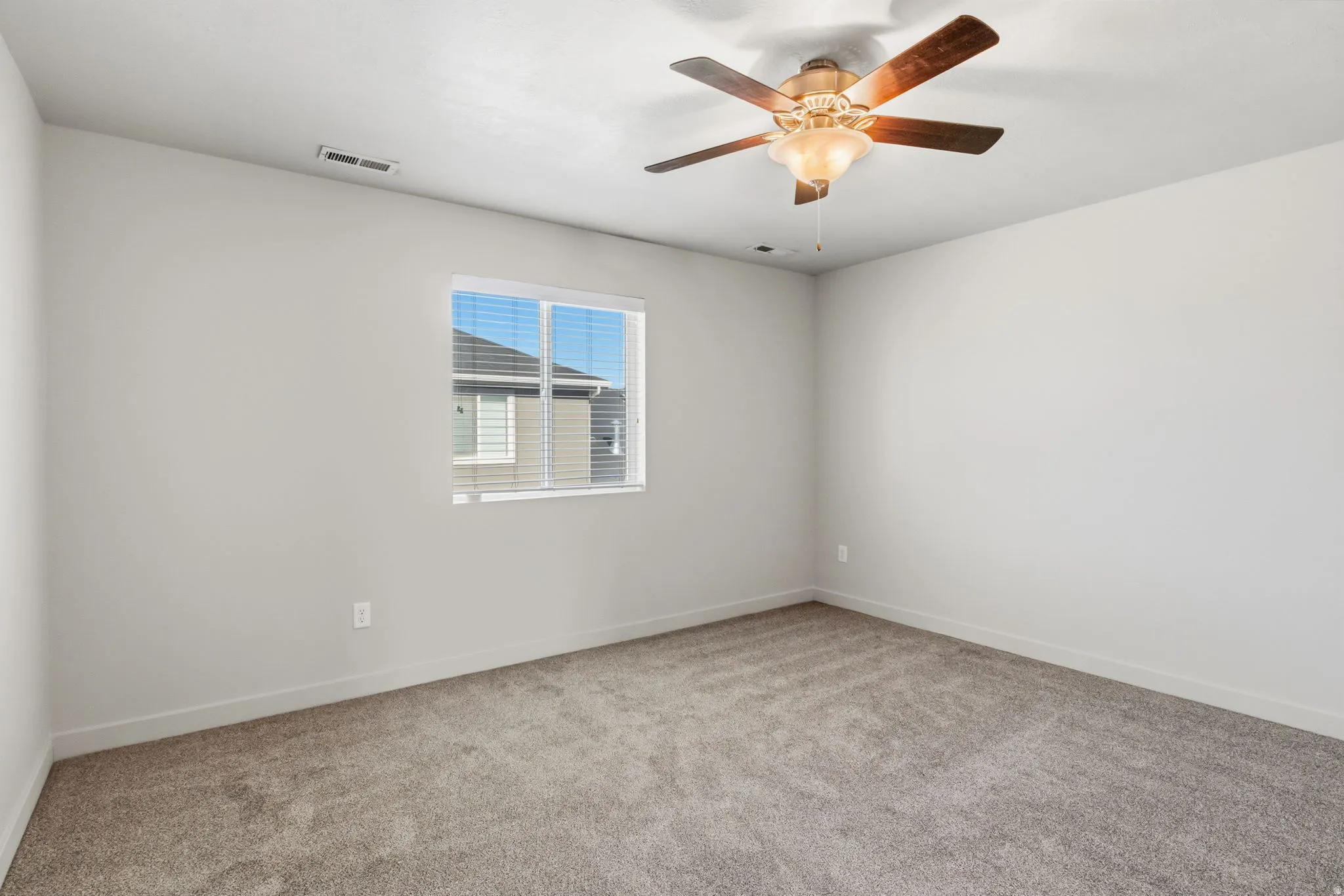 Neutral wall paint, ceiling fan with integrated lighting, window with blinds, and carpet flooring
