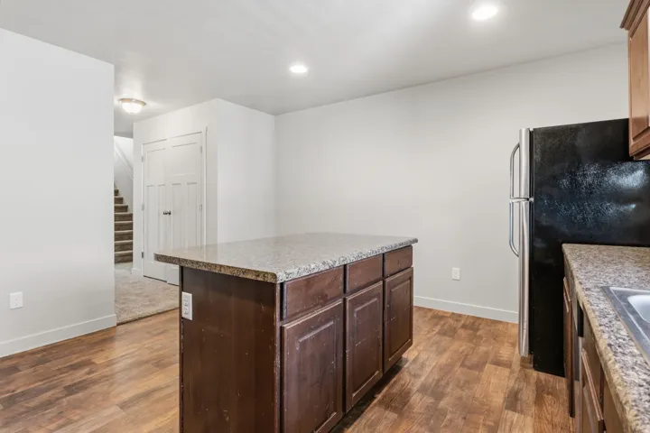 Kitchen featuring a central island with wood-finish cabinetry, stone countertops, and recessed lighting